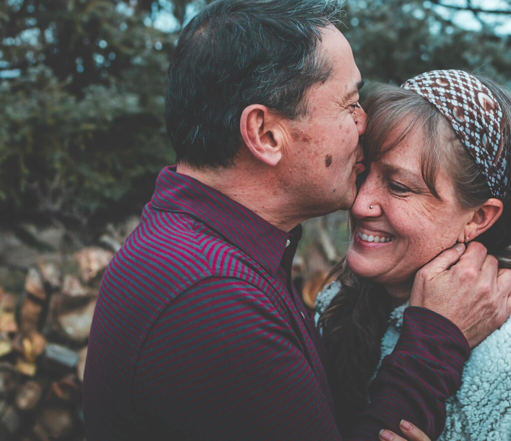 A loving couple shares a tender moment outdoors in a garden setting, expressing happiness and affection.